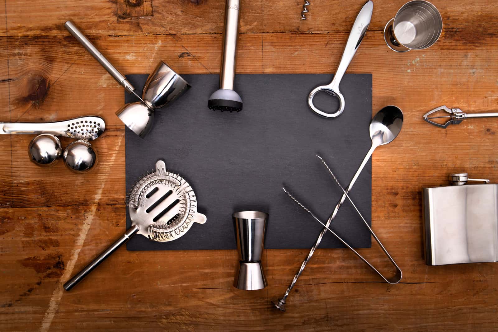 A bartender kit and glassware arranged on a bar surface