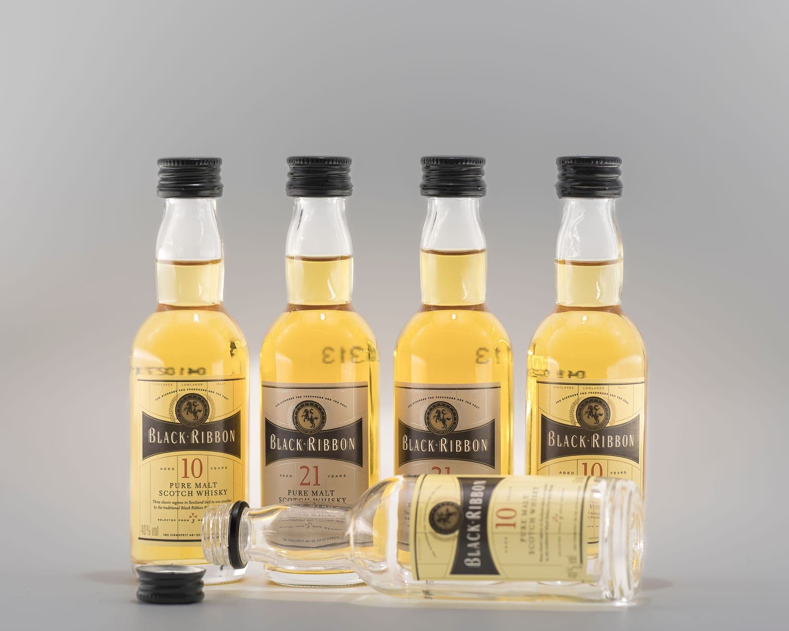A whiskey glass and bottle arranged as a gift on a wooden surface