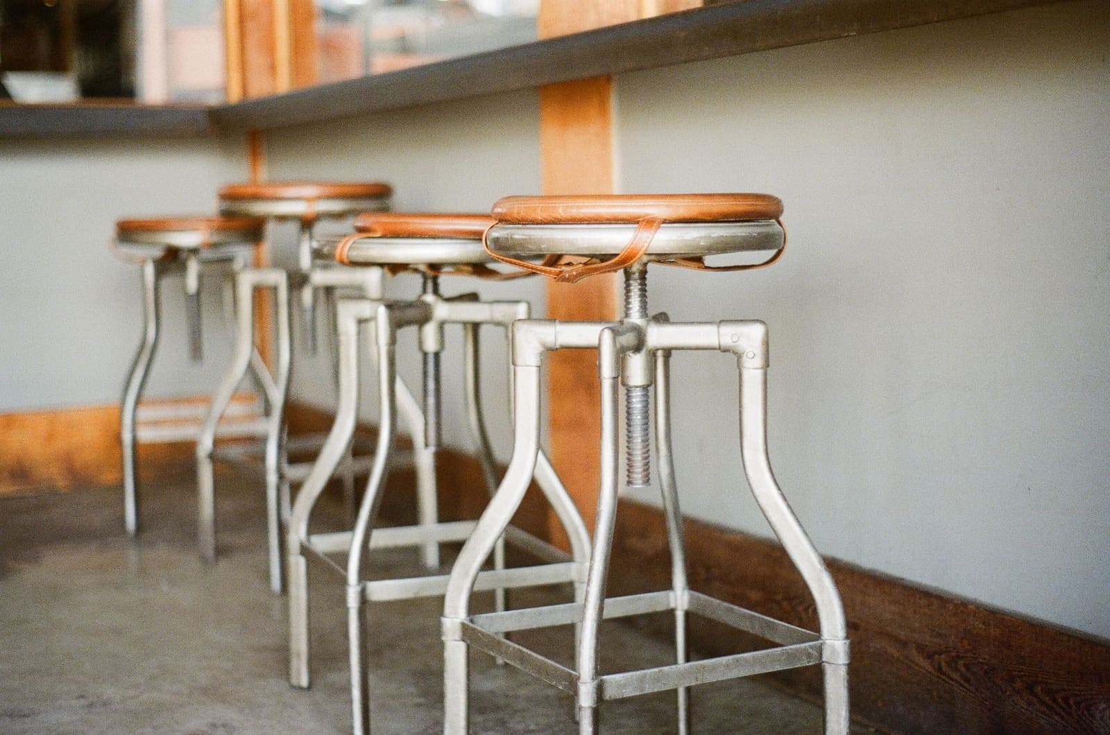Backless stools with wooden seats lined up at a bar
