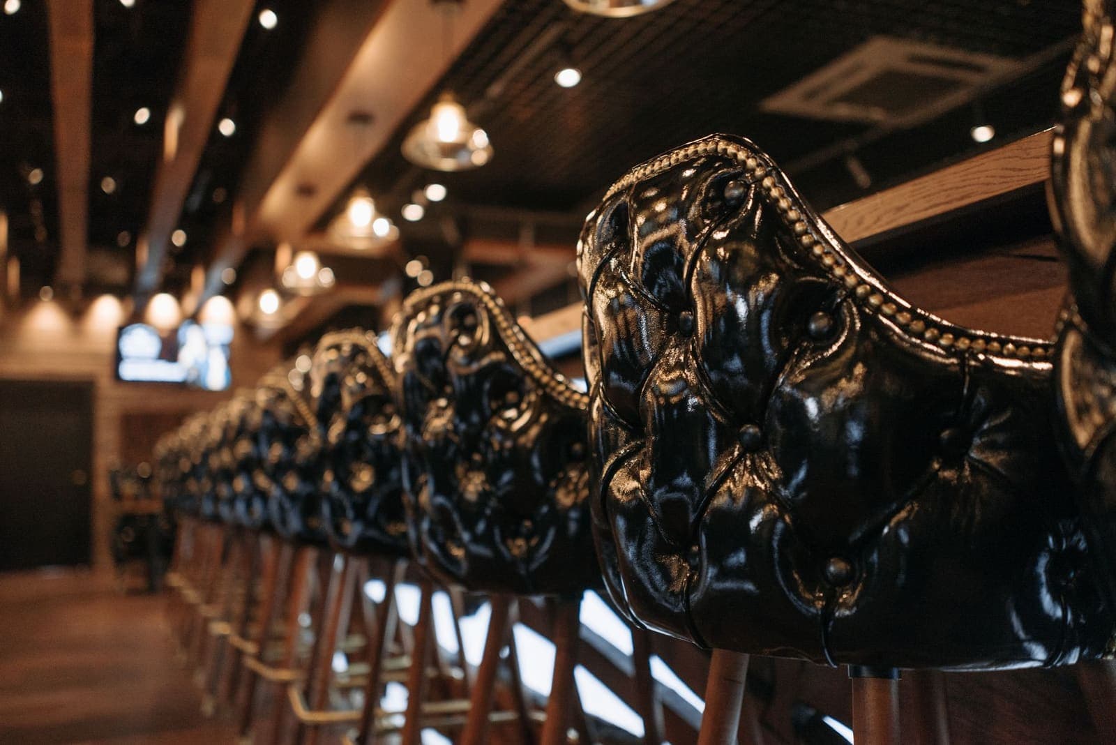 A row of upholstered leather stools along a bar counter