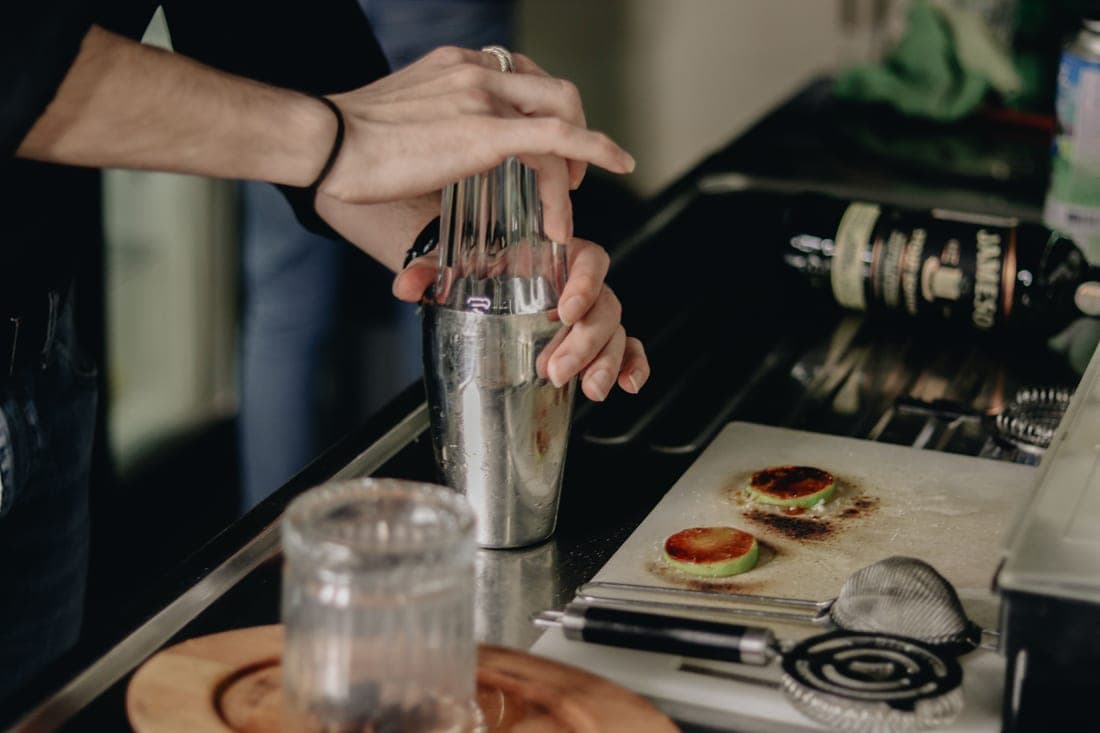 A three-piece cobbler shaker beside a finished cocktail
