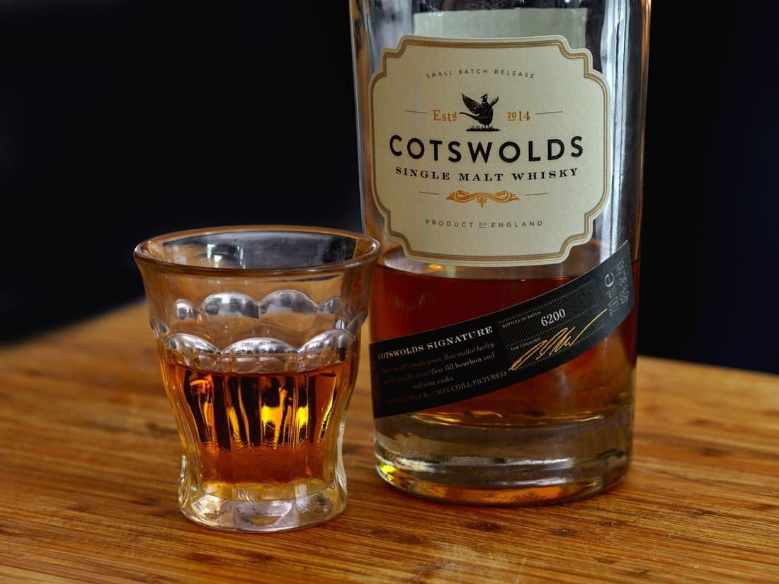 A crystal tumbler on a wooden bar with warm backlight