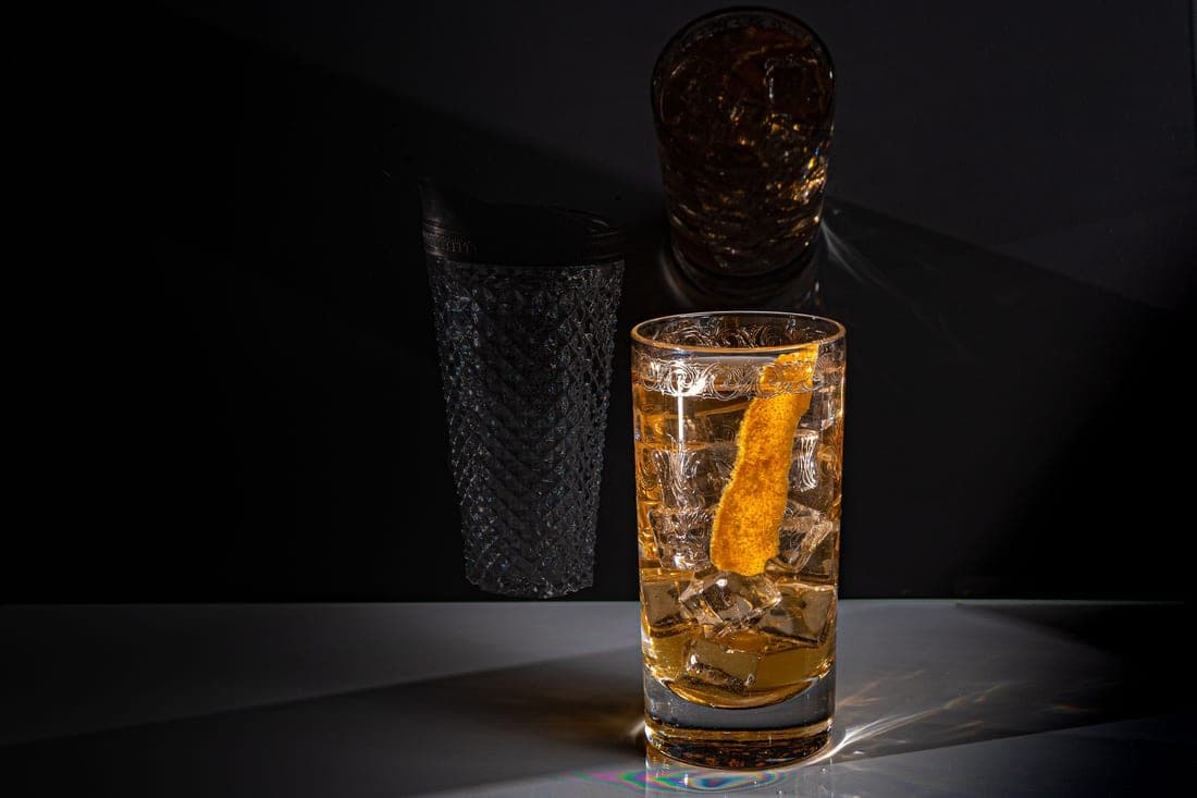 A faceted rocks glass catching warm light on a bar