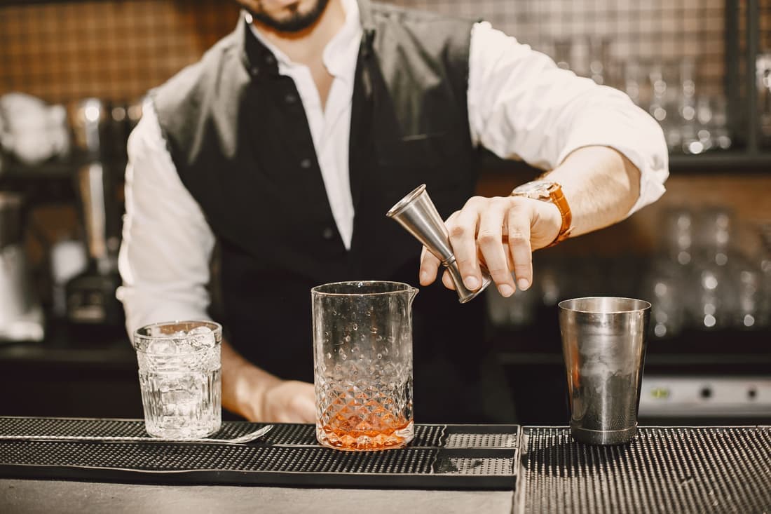 A stainless double jigger resting beside citrus and a knife