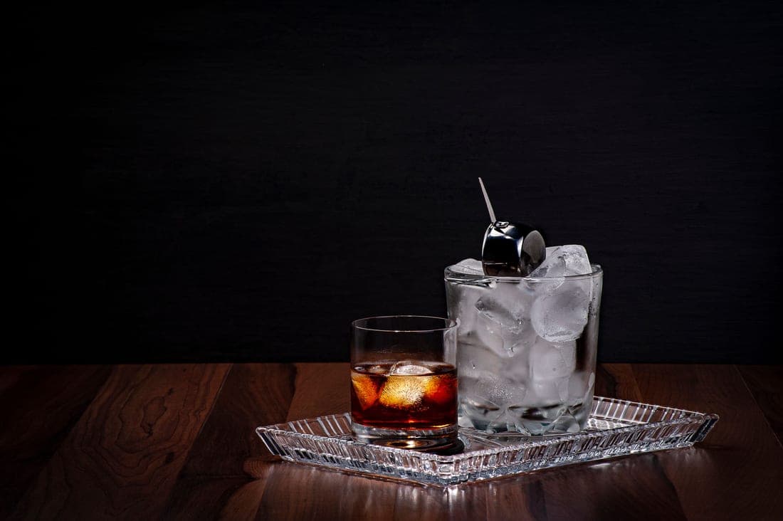 A large seamless mixing glass holding clear ice and spirit