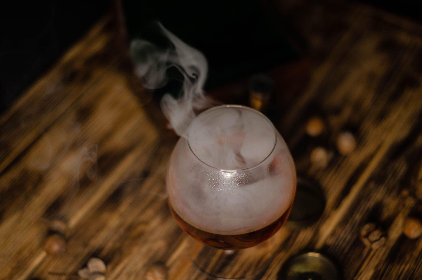 A wooden smoke lid on a rocks glass with wood chips beside it
