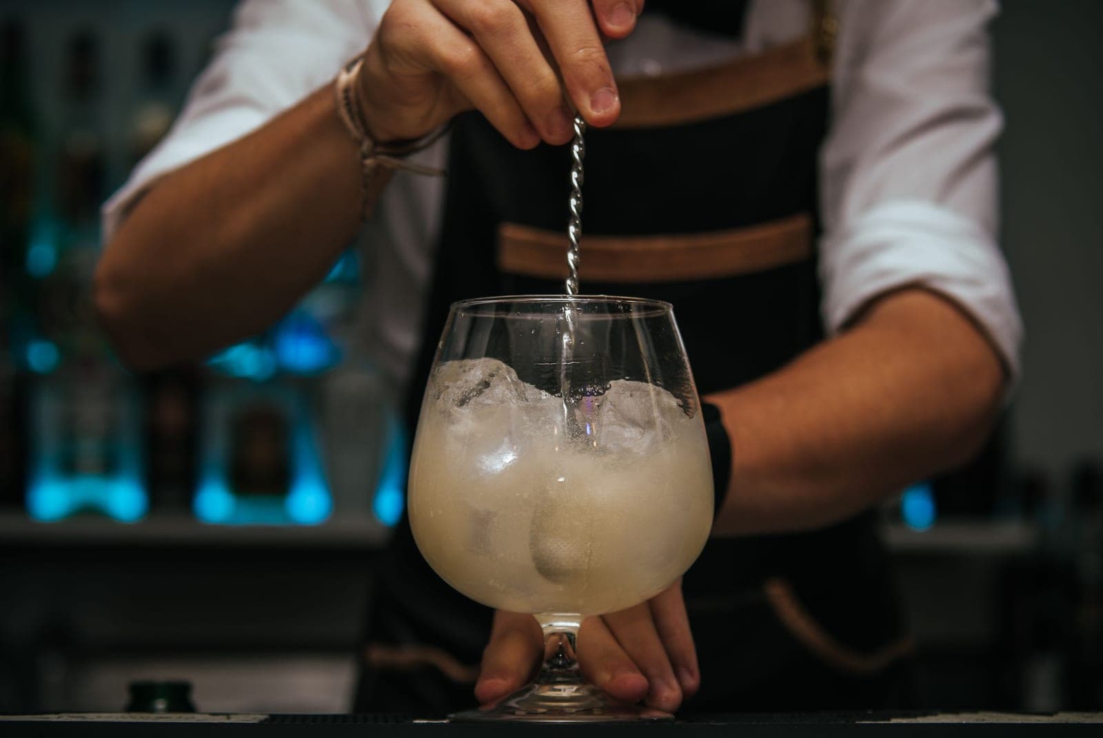 A cocktail being stirred with a long spoon in a mixing glass